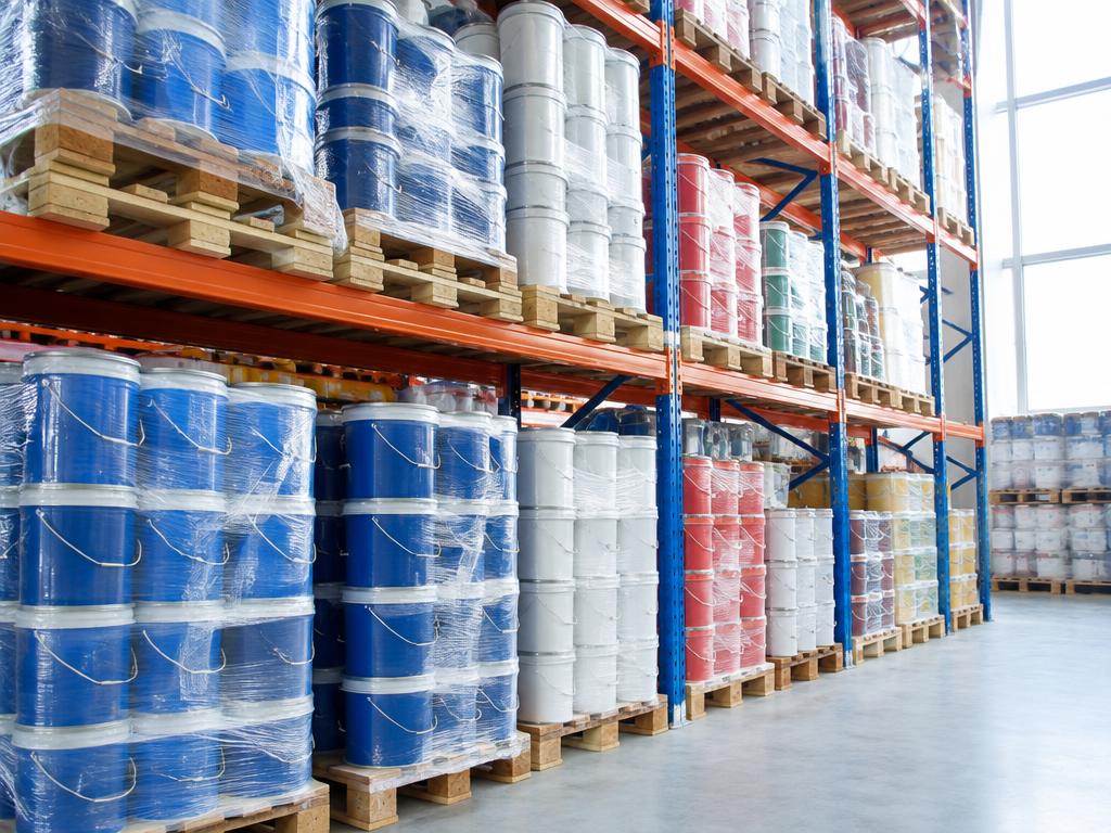 Warehouse racking stacked with wrapped pallets of paint tins